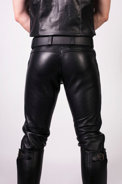 Person wearing black leather pants and boots on a white background