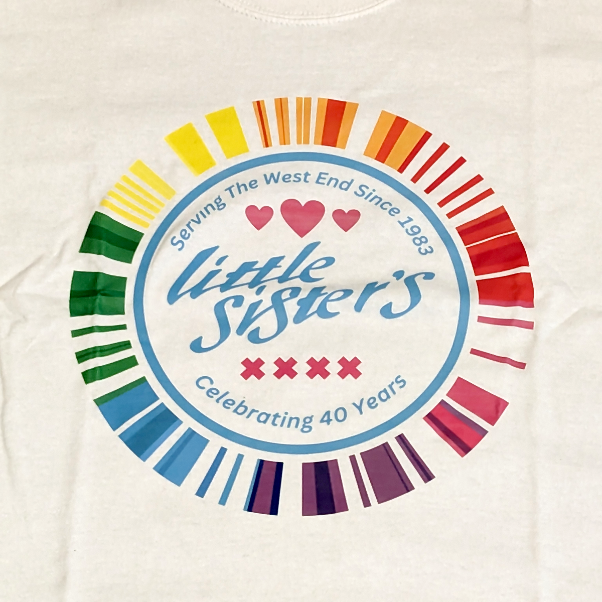 White t-shirt with 'little sisters' logo featuring rainbow colors and text on a white background